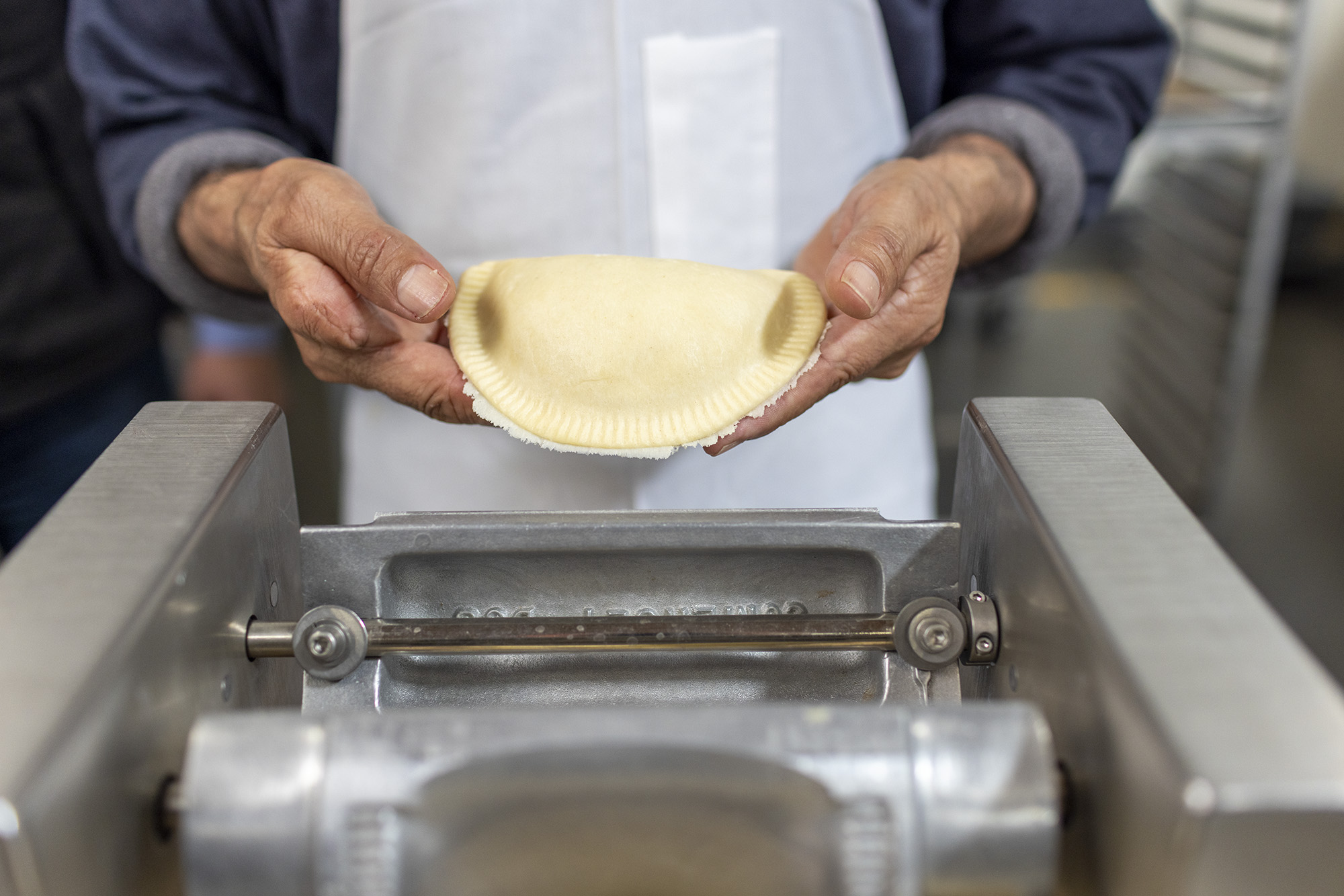 Person holding freshly pressed empanada before going into the oven.