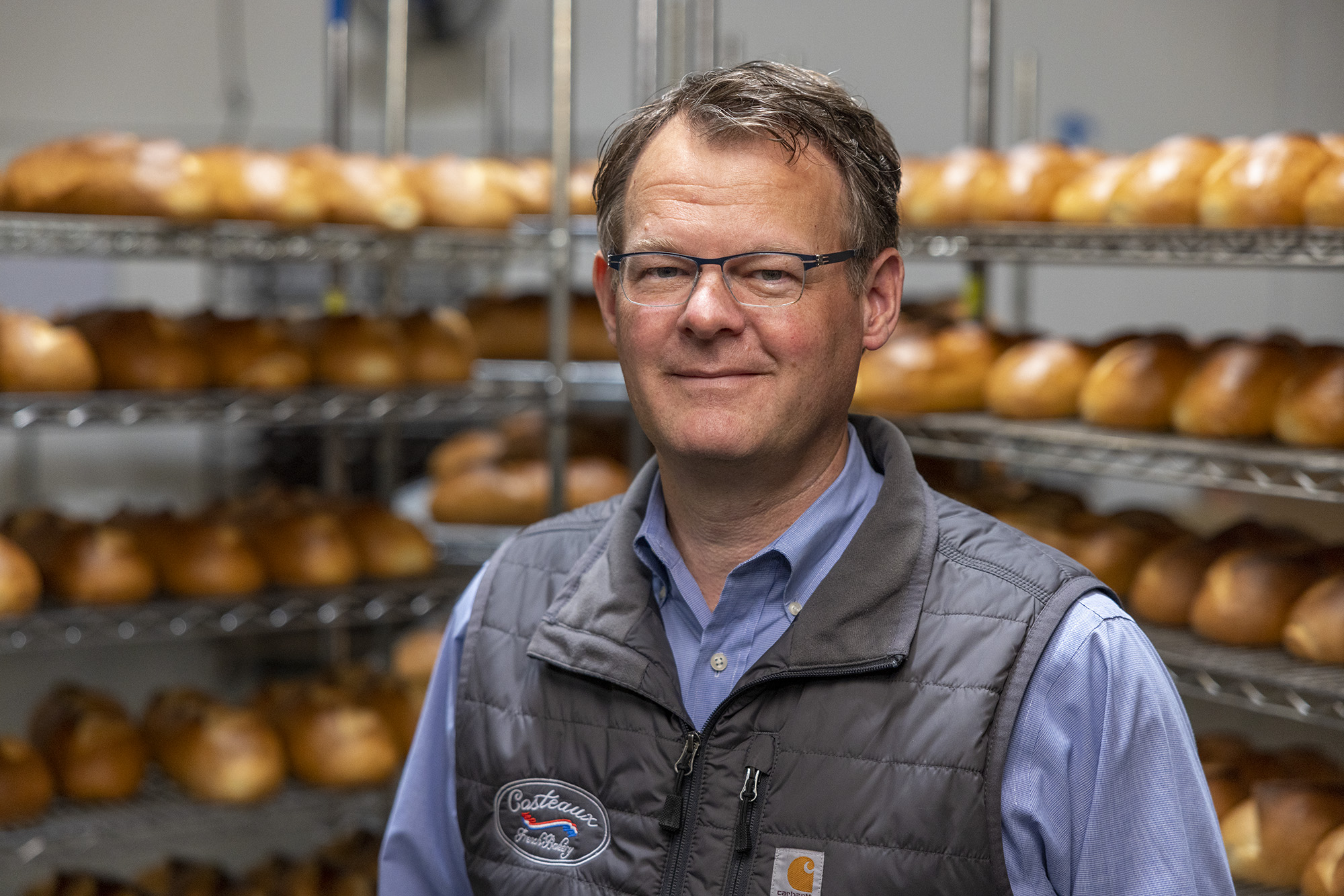 Costeaux French Bakery owner, Will Seppi, posing for camera, surrounded by fresh baked bread.
