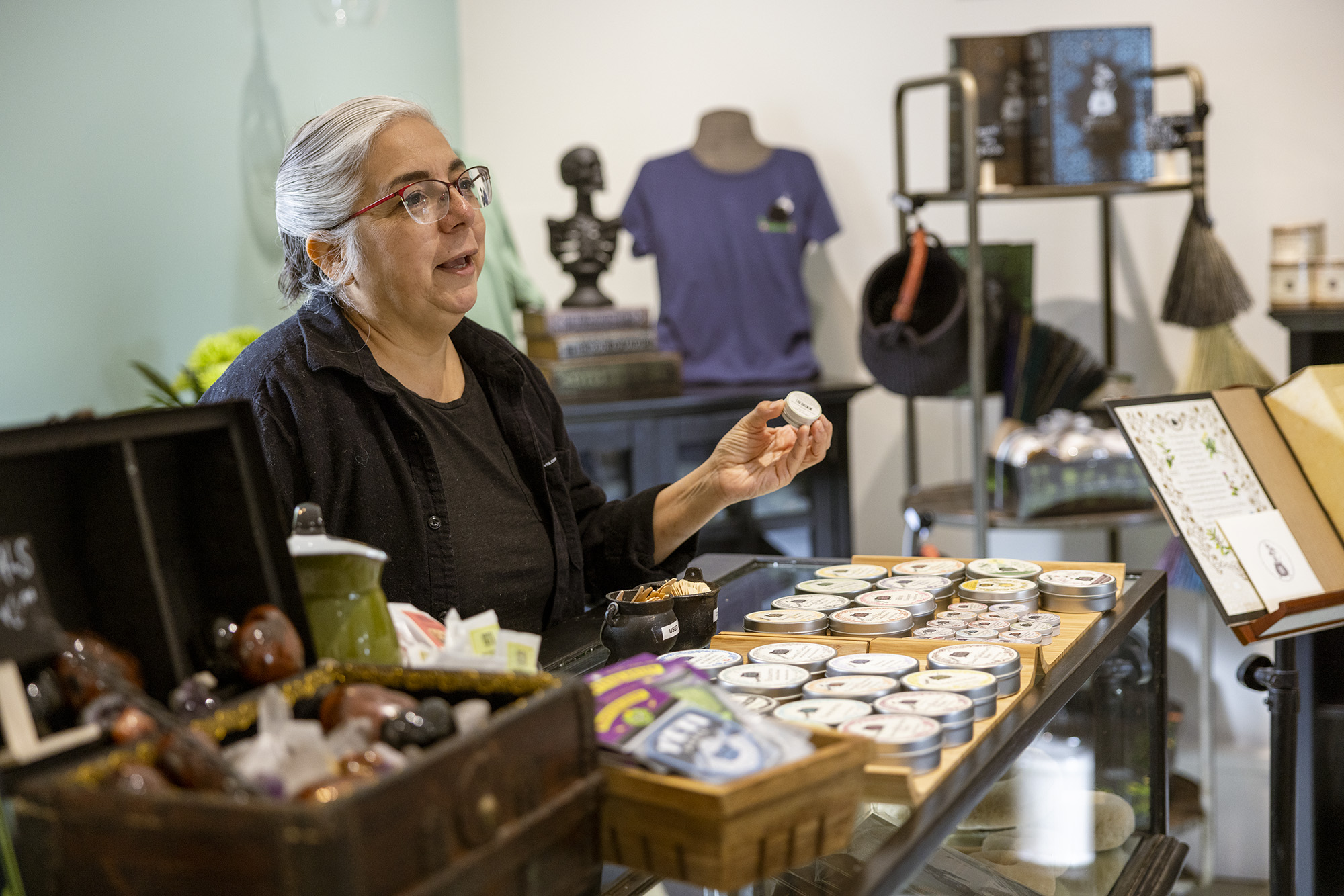 Owner and founder of Soap Cauldron, Emma Mann, standing behind retail counter with product tester in hand.