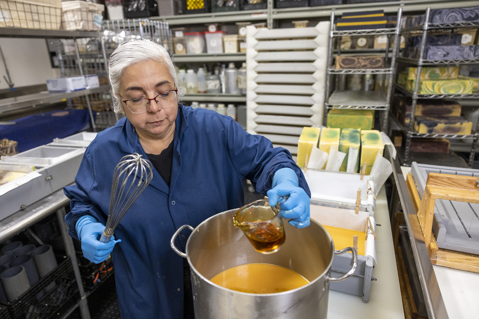 Owner and founder of Soap Cauldron, Emma Mann, pouring essential oils into large pot to make soap