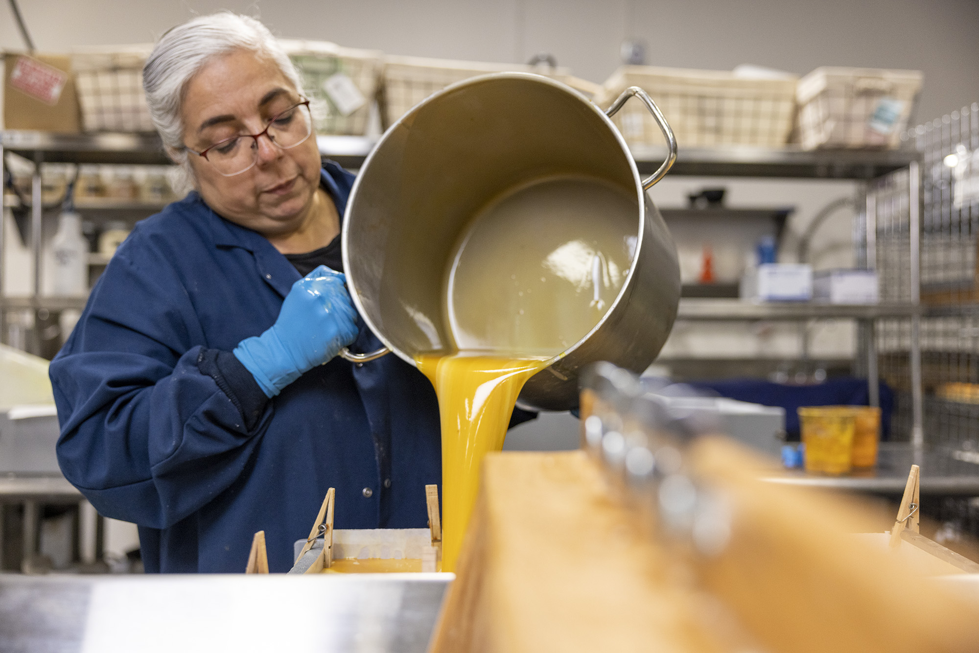 Owner and founder of Soap Cauldron, Emma Mann, pouring large pot of soap into pan to let soap solidify,