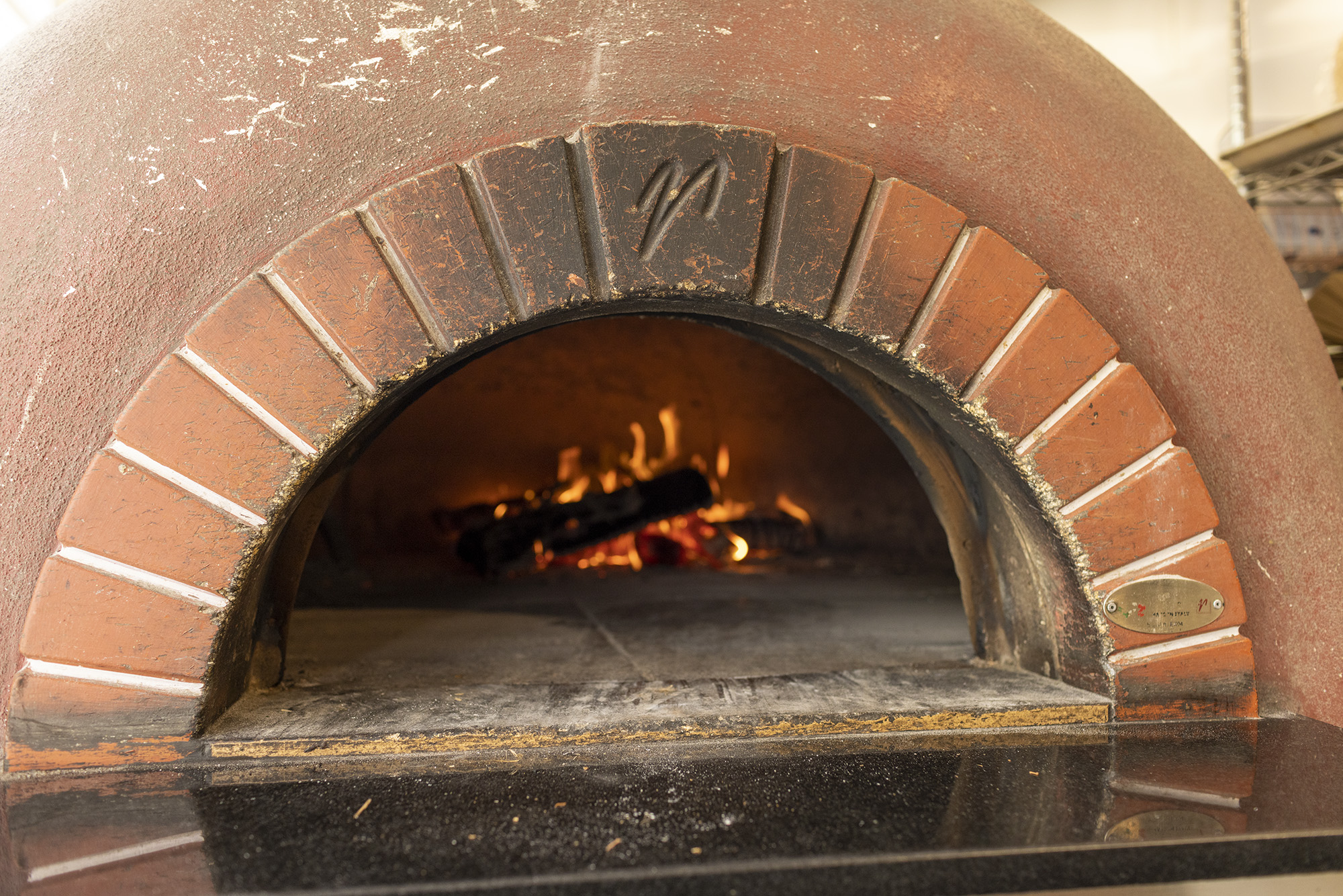 Mugnaini Pwood fire pizza over with fire inside.